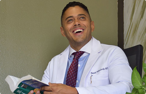 Dr. Daniel Whitelocke reading a book and smiling.