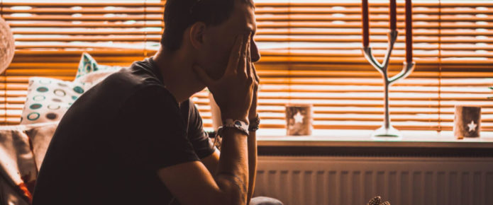 Male PTSD sufferer sitting with head in hands