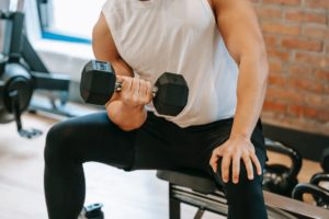 Text: Man Seated While Lifting Weights