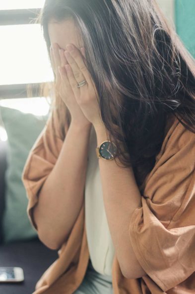 A woman covering her eyes in distress