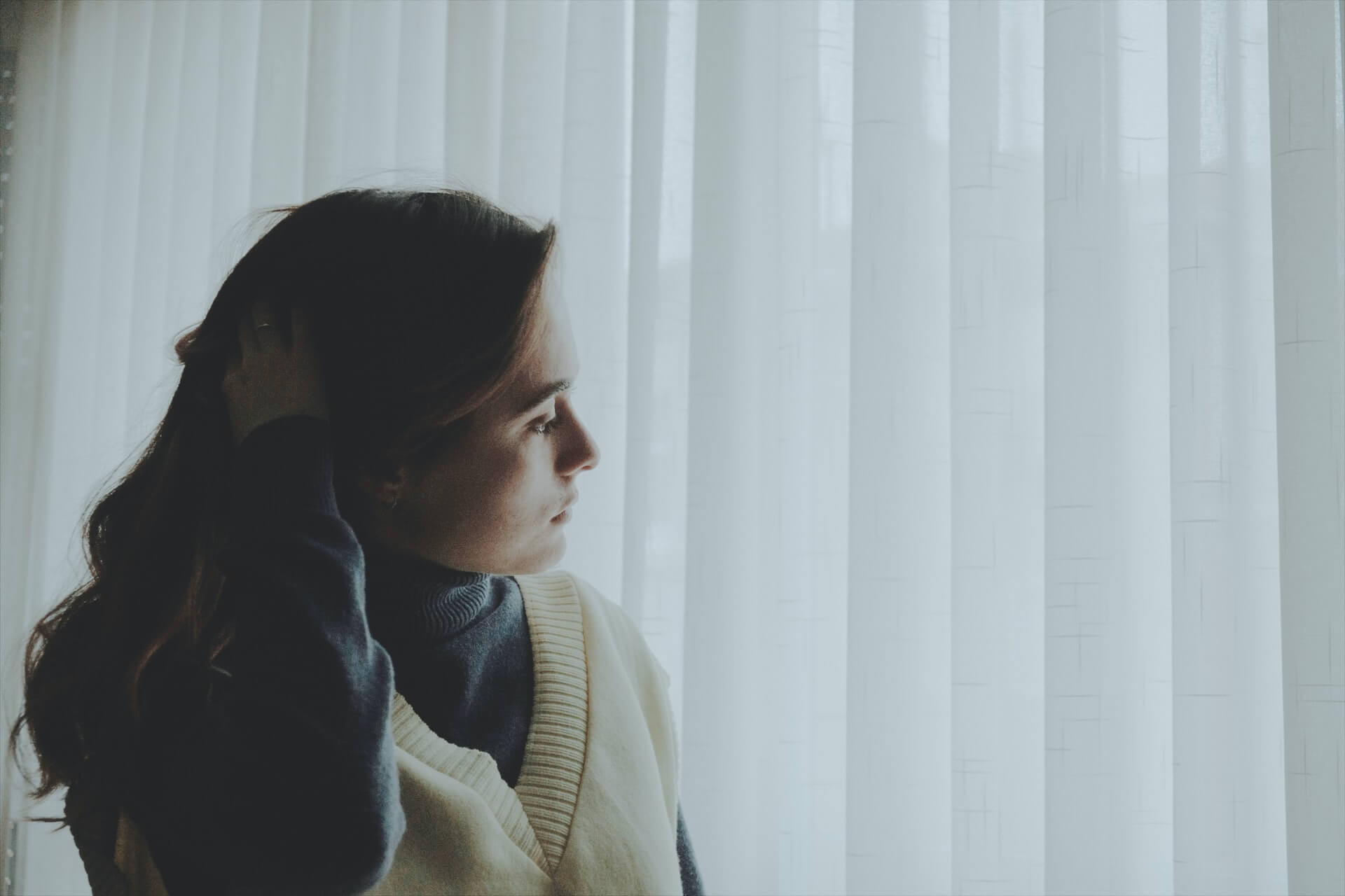 A woman look contemplative next to a window