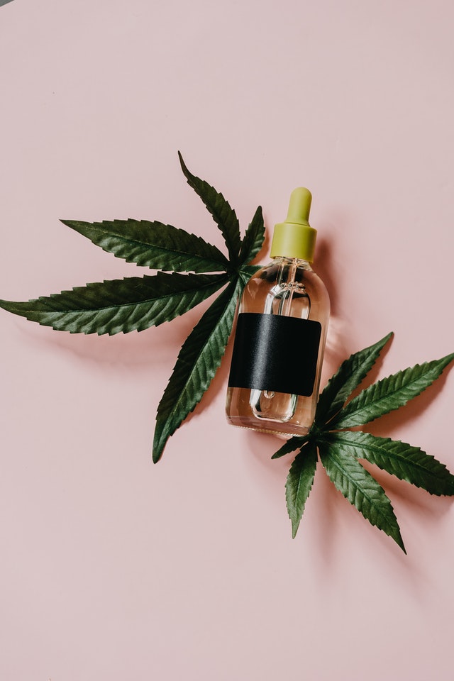 A bottle of CBD oil with some marijuana leaves