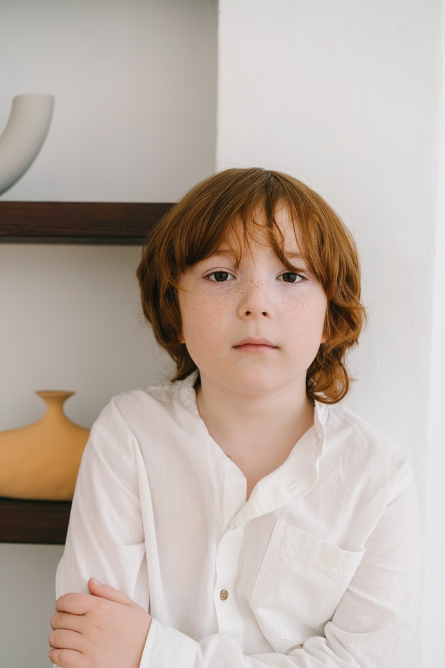 Little boy wearing a white button-up shirt looking at the camera