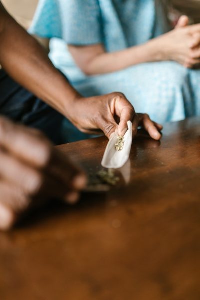 A man rolling up a blunt with medical marijuana while a patient sits in the background