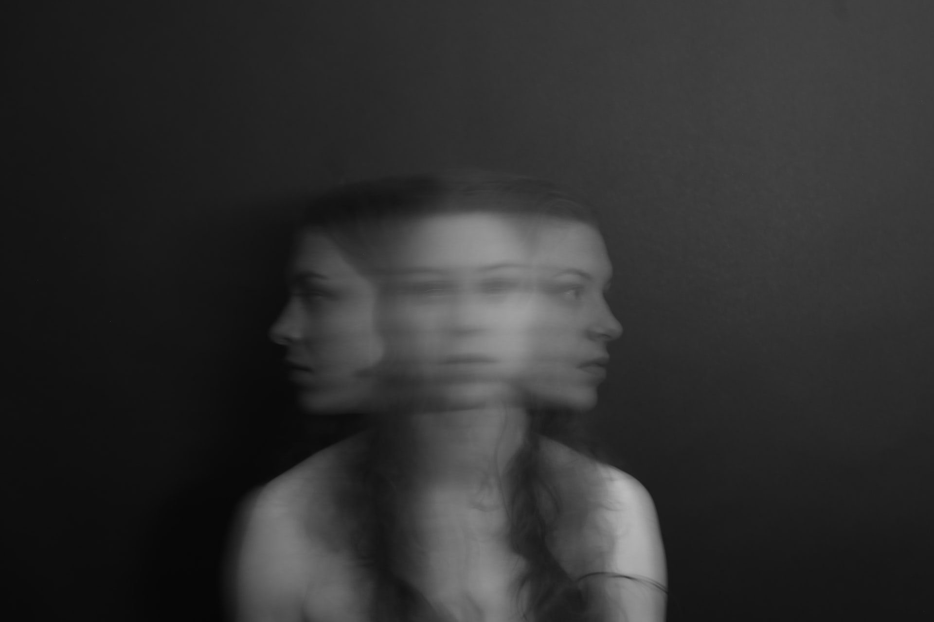 A woman moving her head quickly from side to side so there are three different views of her face merged as one.