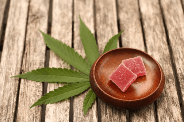 Pink gummies on a brown dish with a cannabis leaf