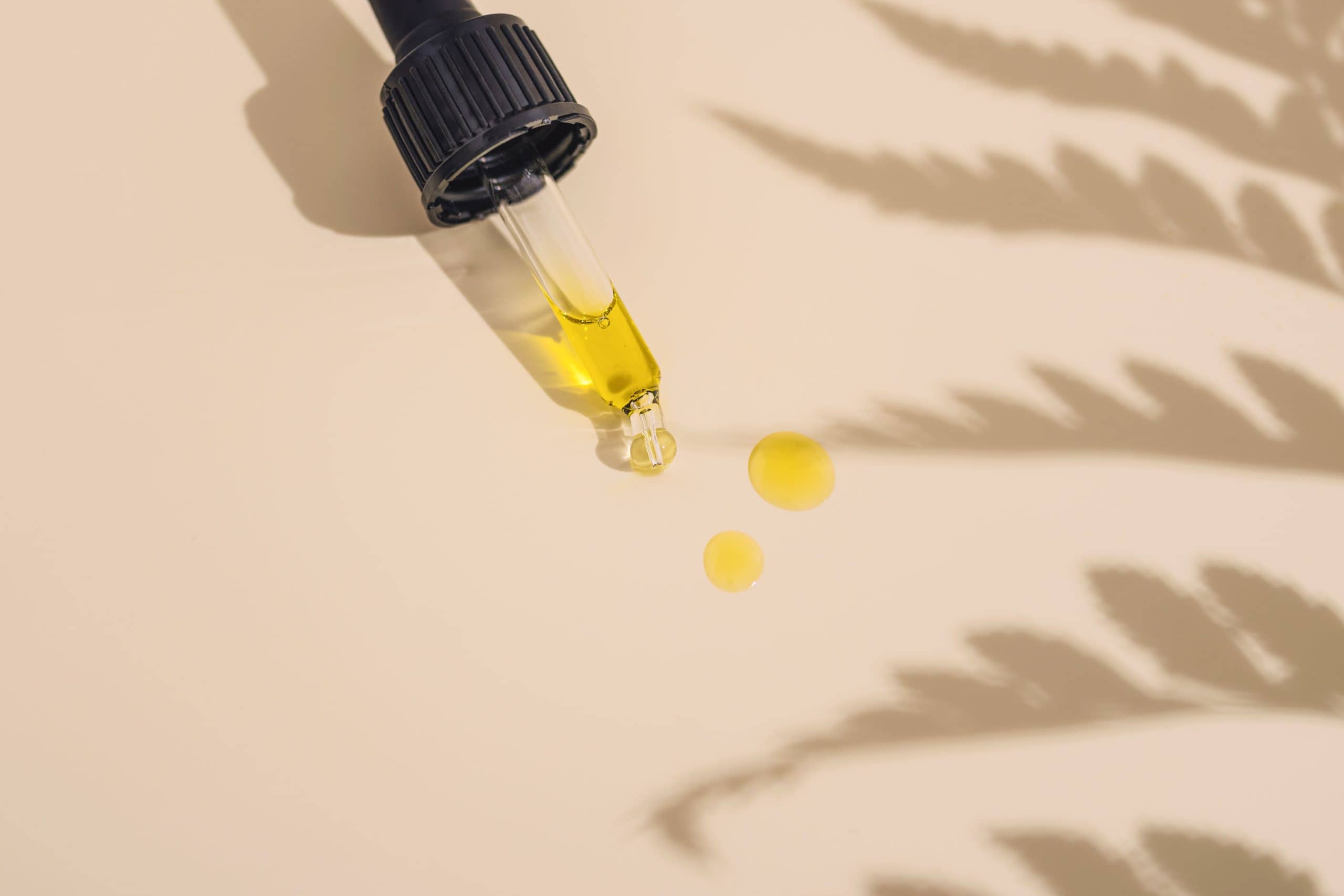 A dropper with tincture laying on a counter with some drops of liquid