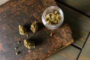 Marijuana buds in a glass jar and on a wooden board