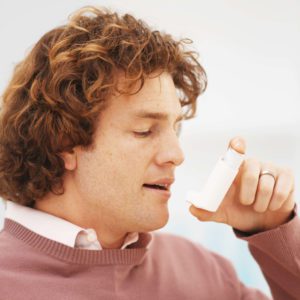 A young man using an inhaler