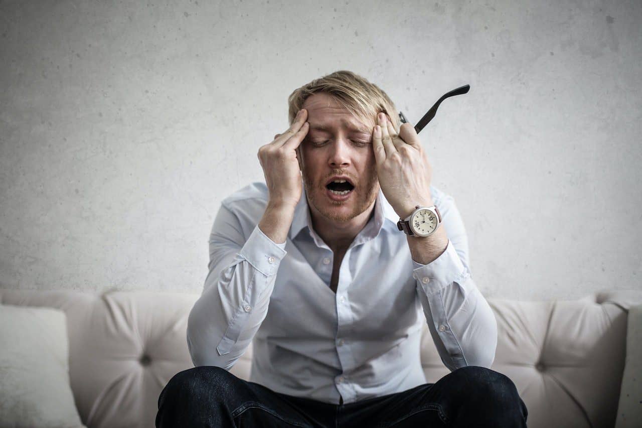 A man touching his head and feeling overwhelmed