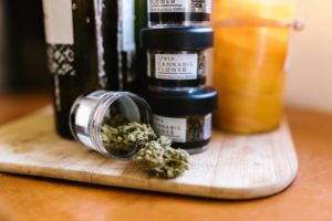 Marijuana buds in a glass jar on a wooden board