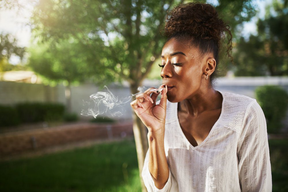 Woman smoking cannabis cigarette outdoors on a sunny day