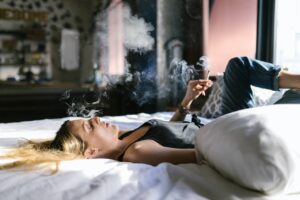 A woman lying in bed and smoking marijuana