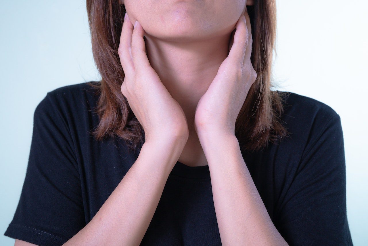 A woman touching her inflamed tonsils