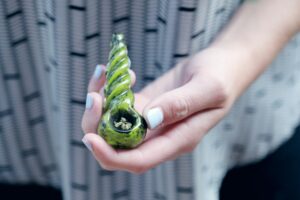 A person holding a pipe with marijuana