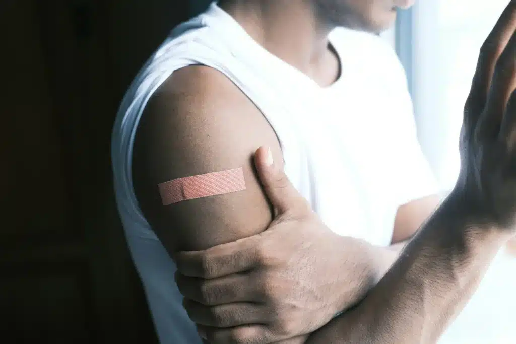 Person holding their upper arm with a bandage, understanding the science behind immune response and healing after injection.