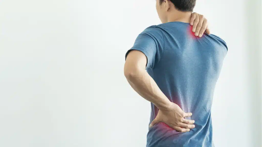 Person holding their neck and lower back to illustrate what causes back pain
